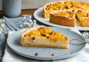 Anschnitt mit Orangen und Pinienkernen belegter Ricottakuchen